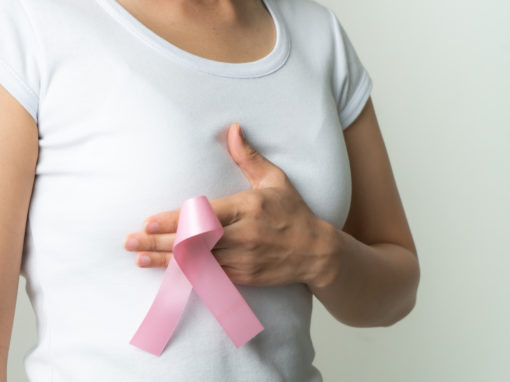 woman holding breast cancer awareness ribbon to her chest
